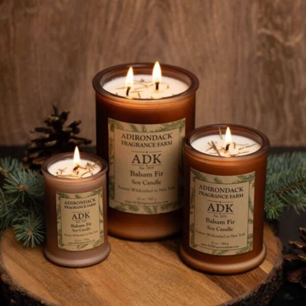 Balsam Fir Candle trio with an ADK Label on a wooden plate and lit flame