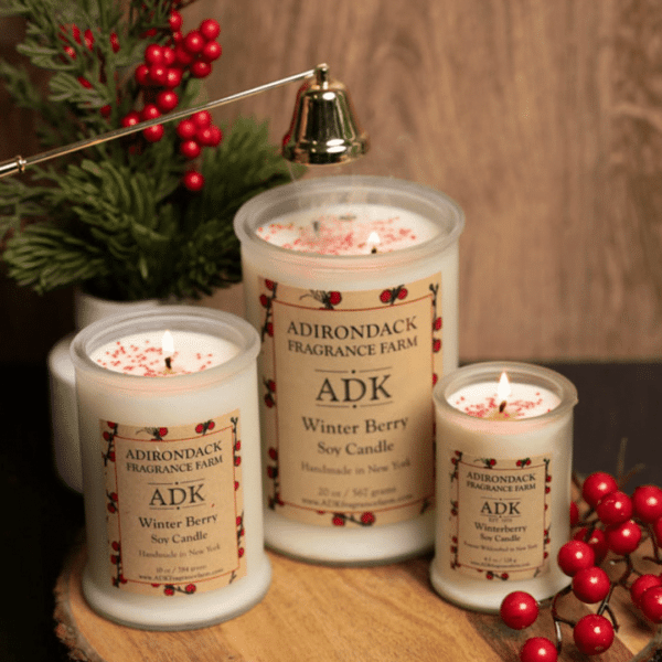 3 sizes of frosted white candles on a wooden background with winter berry branches