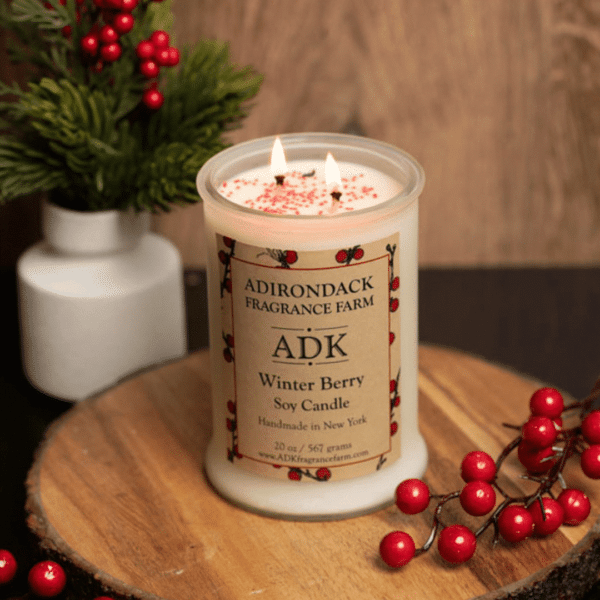 Frosted white candle on a wooden background with winter berry branches