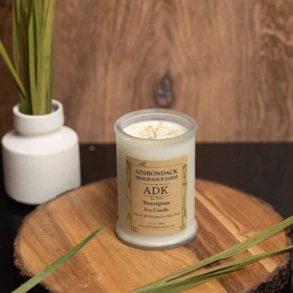Sweetgrass Candle 10oz with ADK label on a wooden plate
